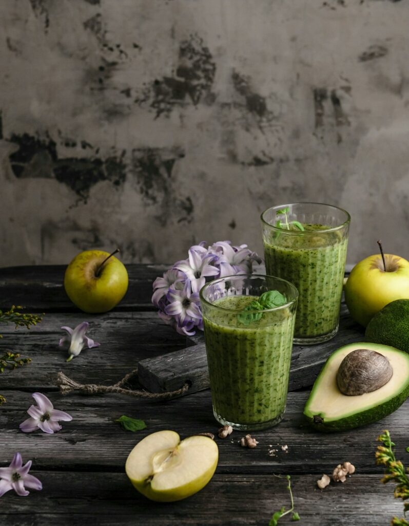 Delicious detox smoothie on rustic wooden board with fruits and flowers