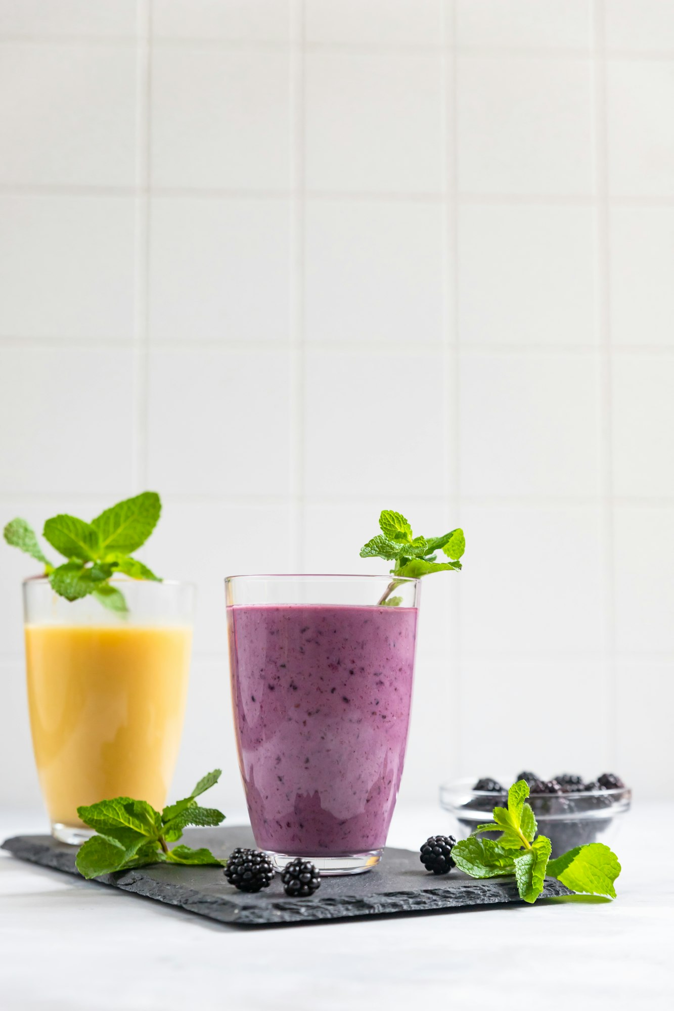 Purple and yellow fruit smoothies or milkshakes with blackberry and mint